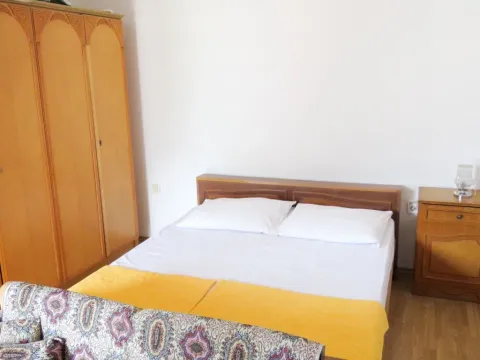Spavaća soba sa bračnim krevetom, drvenim ormarom i noćnim stočićem. - image 9