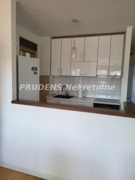 Pogled na kuhinju sa belim elementima i šankom. - image 3
