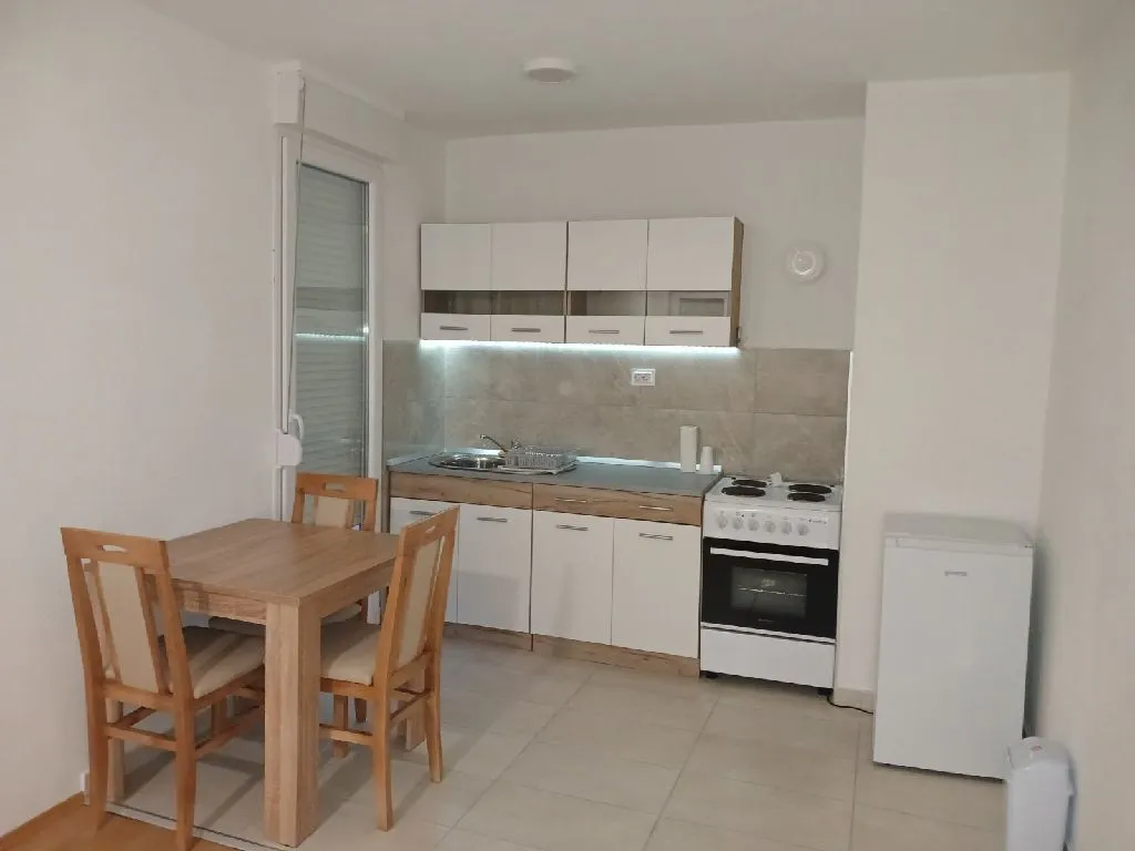 Small kitchen with a dining table and white goods.