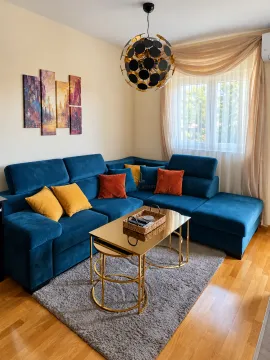 Dnevna soba sa plavom ugaonom garniturom, zlatnim stočićima i modernim lusterom. - image 3