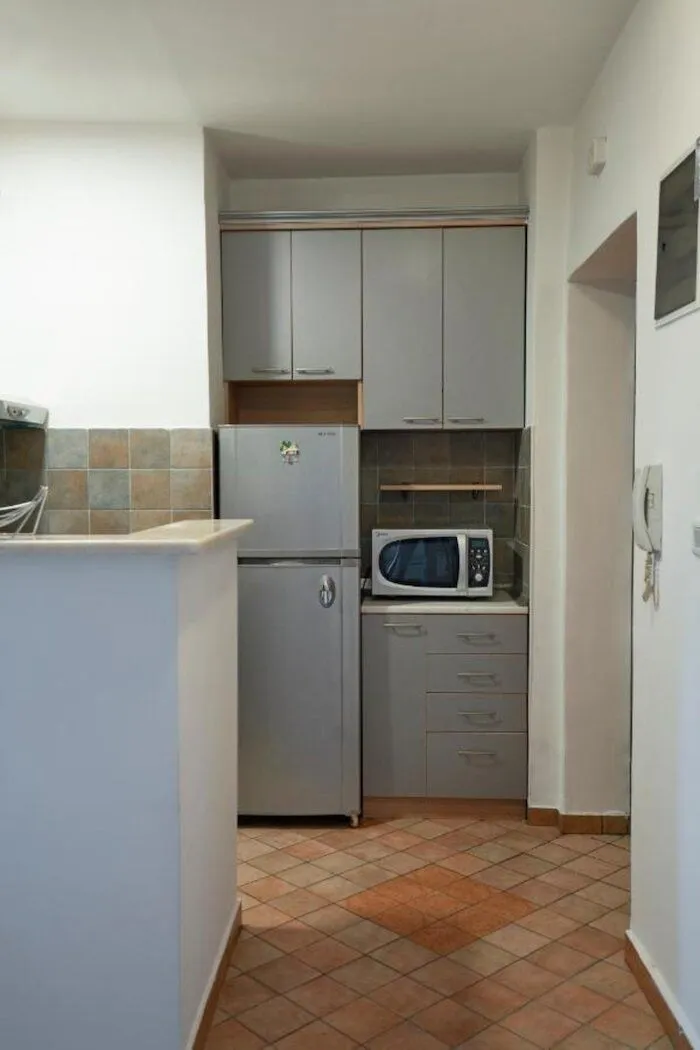Small kitchen with grey cabinets and tiled floor.