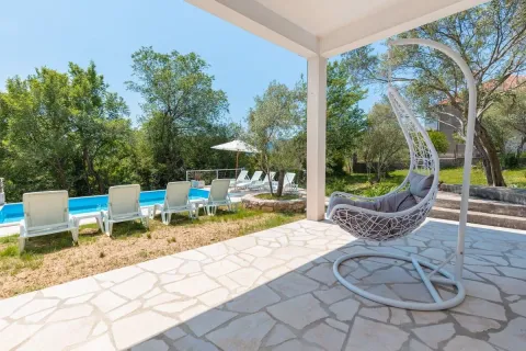 Covered terrace with a hanging chair and a view of the pool and yard. - image 4