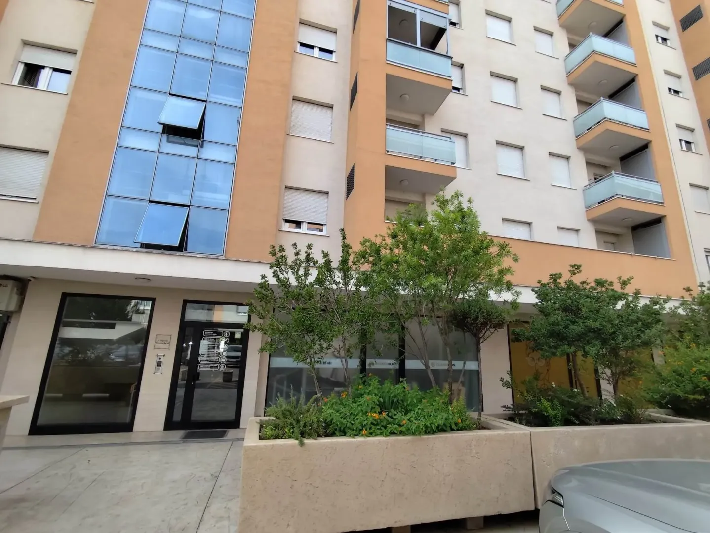 Facade of a residential building with an entrance and landscaped greenery in front.