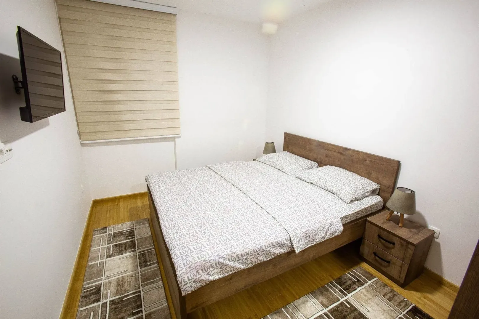 Bedroom with a double bed, nightstands, and a wall-mounted TV.