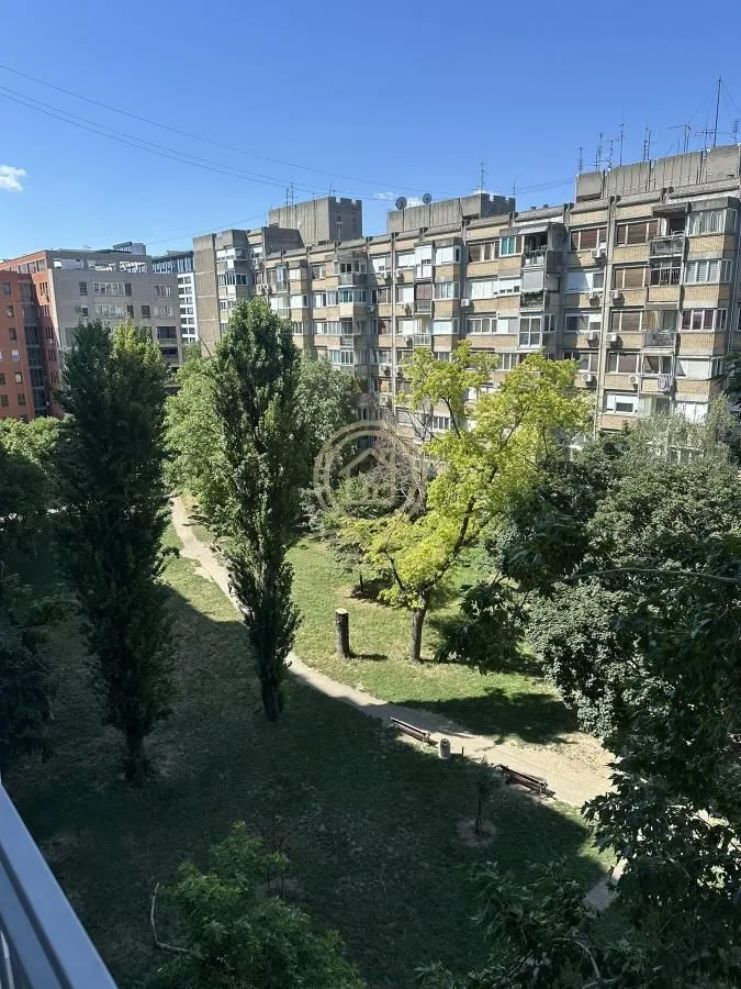 Pogled sa prozora na park i okolne stambene zgrade.