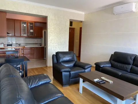 Bright living room with black leather sofas and a view into the kitchen. - image 2