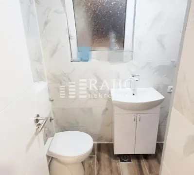 Manje kupatilo sa belim pločicama, umivaonikom i toalet šoljom. - image 12