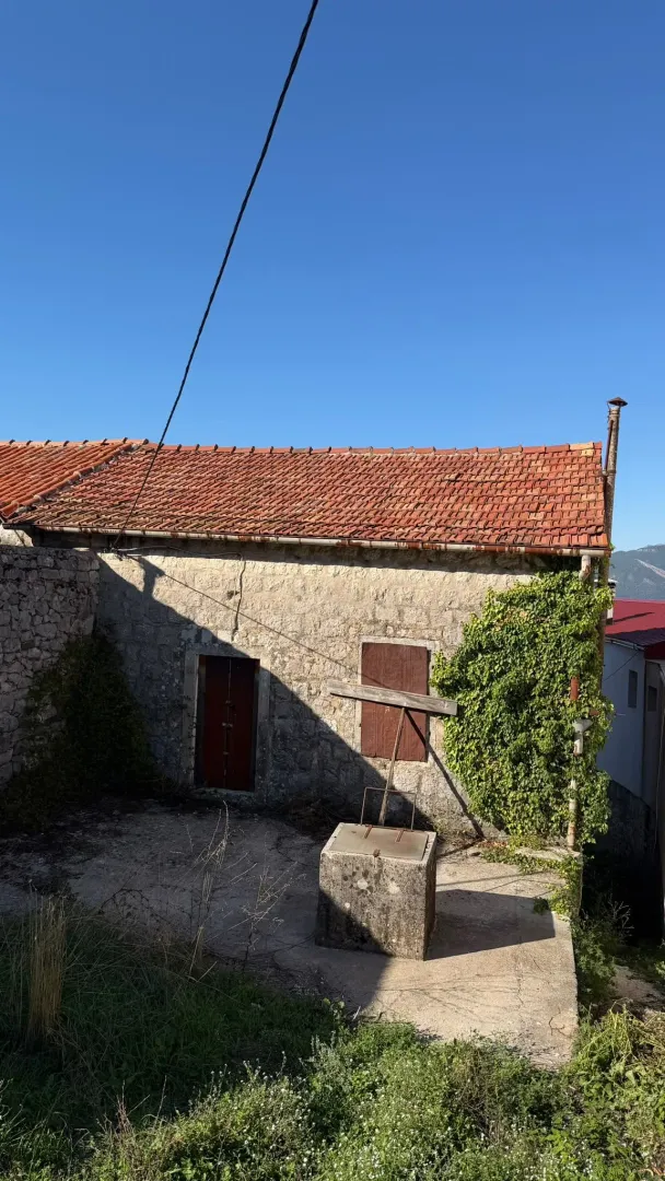 Eksterijer stare kamene kuće sa dvorištem i bunarom.