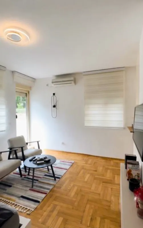 Dnevna soba sa garniturom za sedenje, stočićem i televizorom.