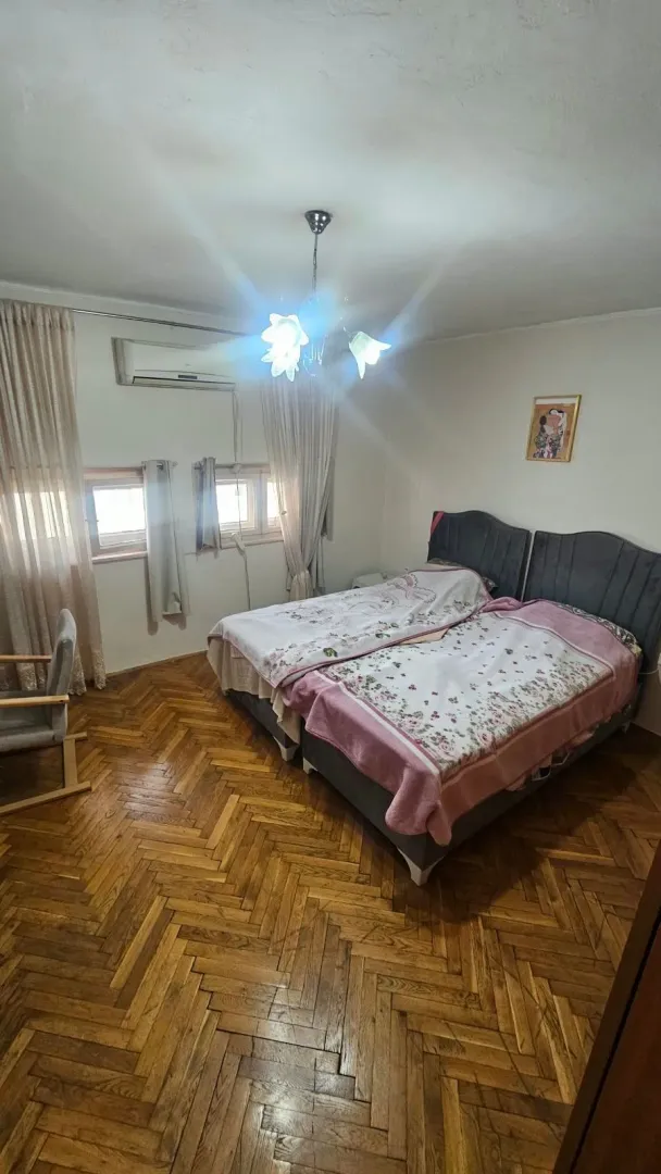 Spavaća soba sa bračnim krevetom, drvenim parketom i klima uređajem.