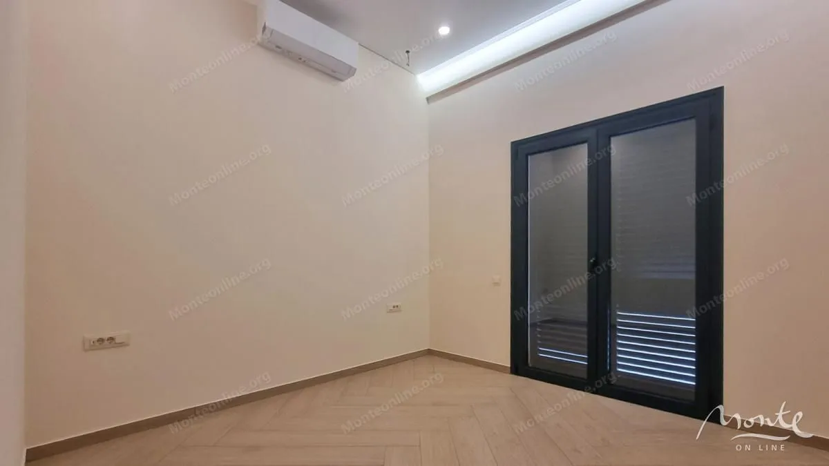 Prazna soba sa klima uređajem i balkonskim vratima.