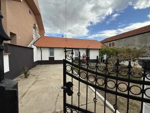 View of the courtyard and single-story house through a black metal gate. - image 14