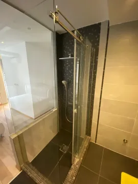 Moderno kupatilo sa staklenom tuš kabinom i tamnim mozaik pločicama. - image 14
