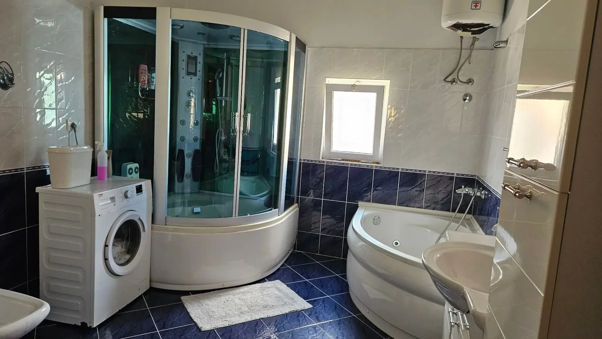 Spacious bathroom equipped with a shower cabin, bathtub, and washing machine.