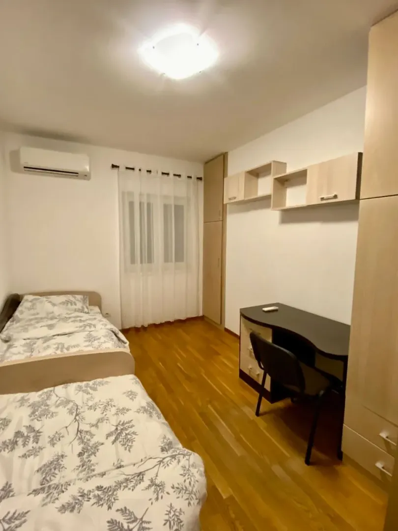 Twin bedroom with beds, a desk, and wardrobes.
