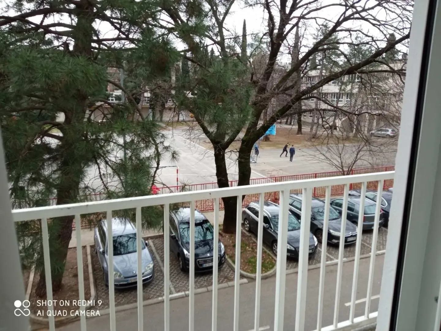 View from a balcony overlooking a parking lot and sports court.