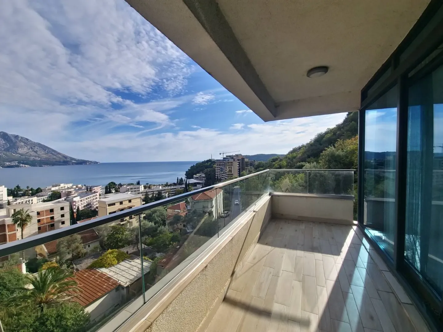 Spacious covered balcony with a glass railing and a view of the sea and surroundings.