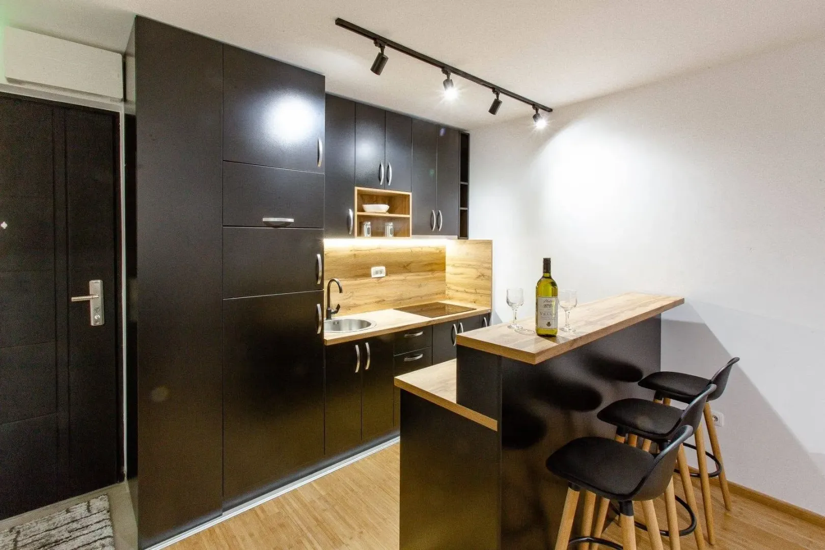 Modern kitchen with dark cabinets and a breakfast bar with stools.
