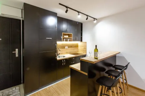 Modern kitchen with dark cabinets and a breakfast bar with stools. - image 4