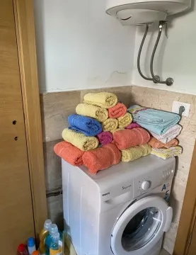 Bathroom with a washing machine and stacked towels. - image 6