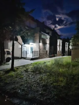 Noćni pogled na spoljašnjost kuće sa osvetljenim ulazom i dvorištem. - image 12