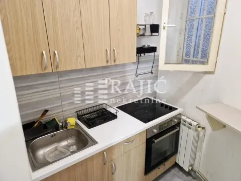 Small kitchen with wooden cabinets, sink, and built-in hob. - image 8
