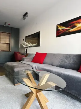 Living room with a sectional sofa, glass coffee table, and decorative details. - image 2