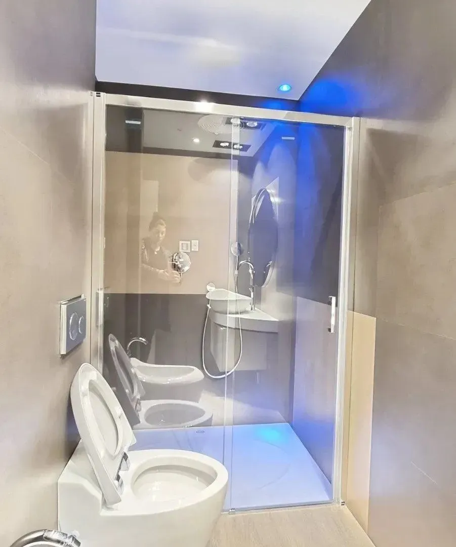 Savremeno opremljeno kupatilo sa tuš kabinom i sanitarijama.