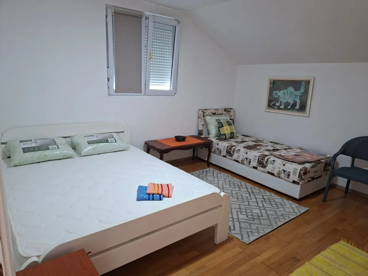 Attic bedroom with two beds and white walls.