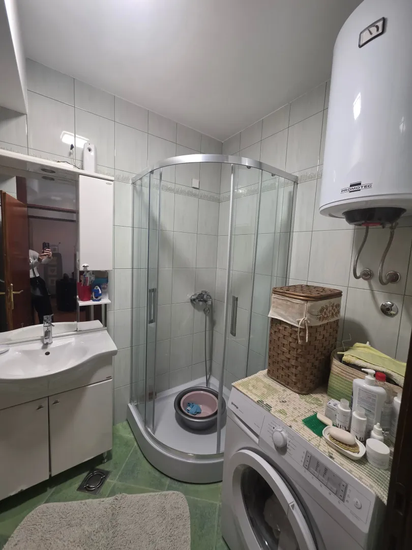 Manje kupatilo sa tuš kabinom, umivaonikom i veš mašinom.