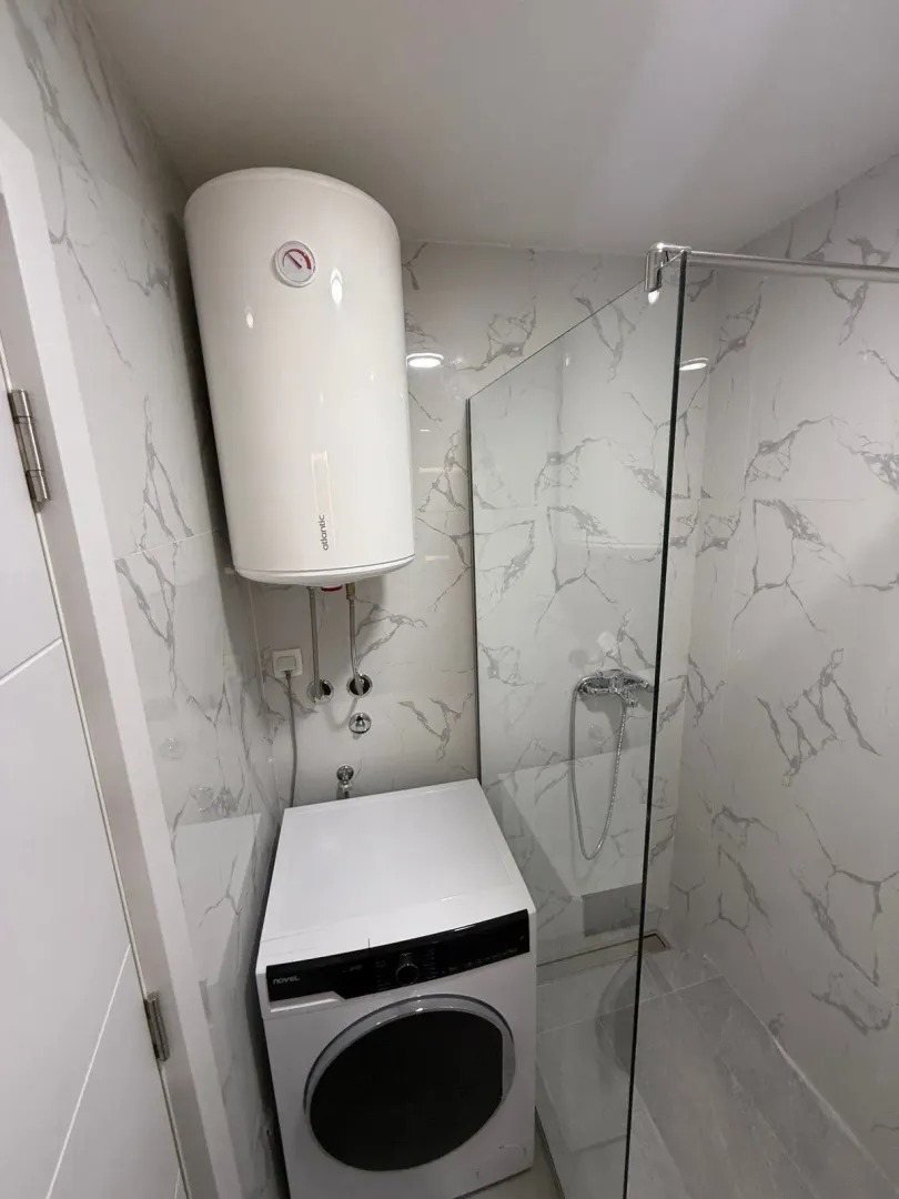 Moderno opremljeno kupatilo sa tuš kabinom, bojlerom i veš mašinom.
