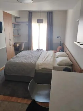 Furnished bedroom with a double bed, wardrobe, and desk. - image 13