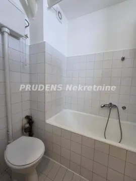 Manje kupatilo obloženo belim pločicama sa kadom i toaletom. - image 11