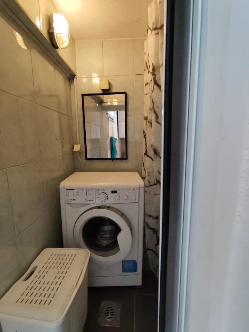 Manje kupatilo sa veš mašinom i tuš kabinom.