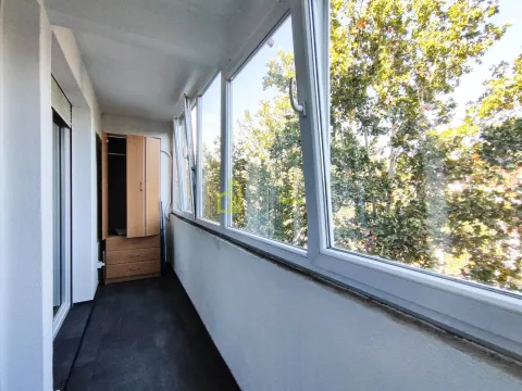 Zastakljeni balkon sa ormarom i pogledom na zelenilo. - image 13