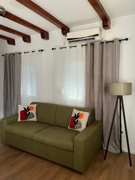 Living room with a green sofa, wooden ceiling beams, and a floor lamp. - image 2