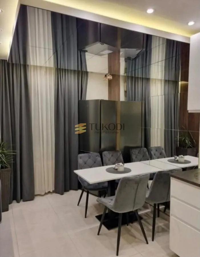 Dining area with a dining table, chairs, and a large wall mirror.