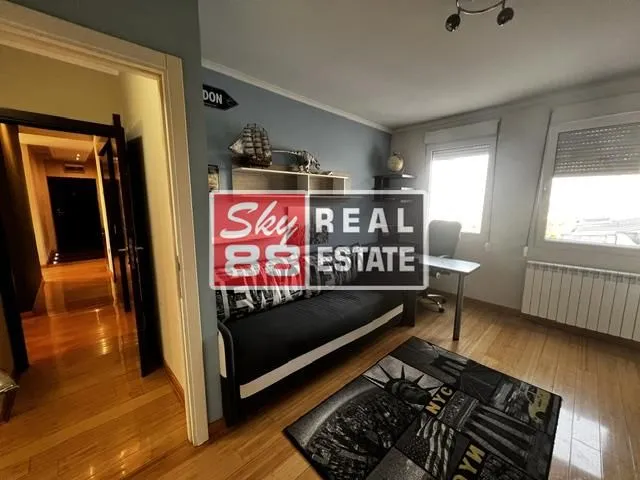 Dečja soba sa krevetom, radnim stolom i policama.