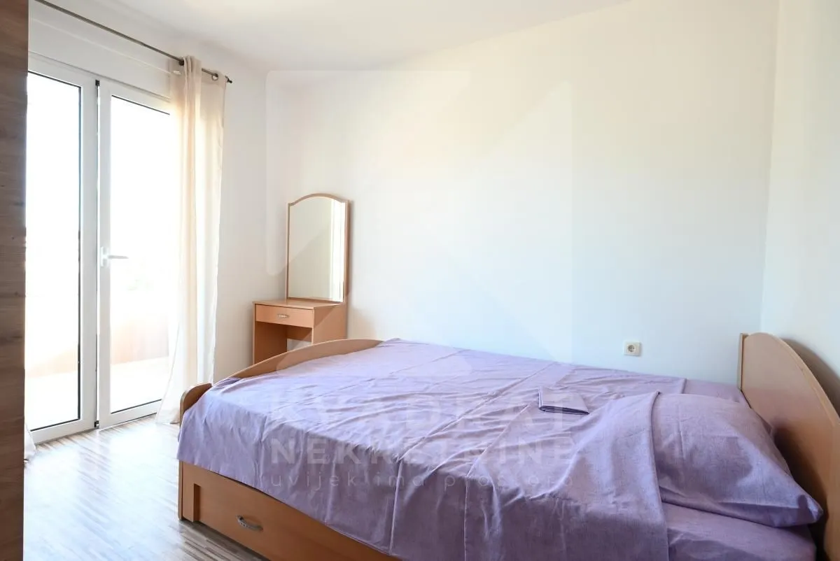 Bedroom with a double bed, wooden dressing table with a mirror, and access to the terrace.