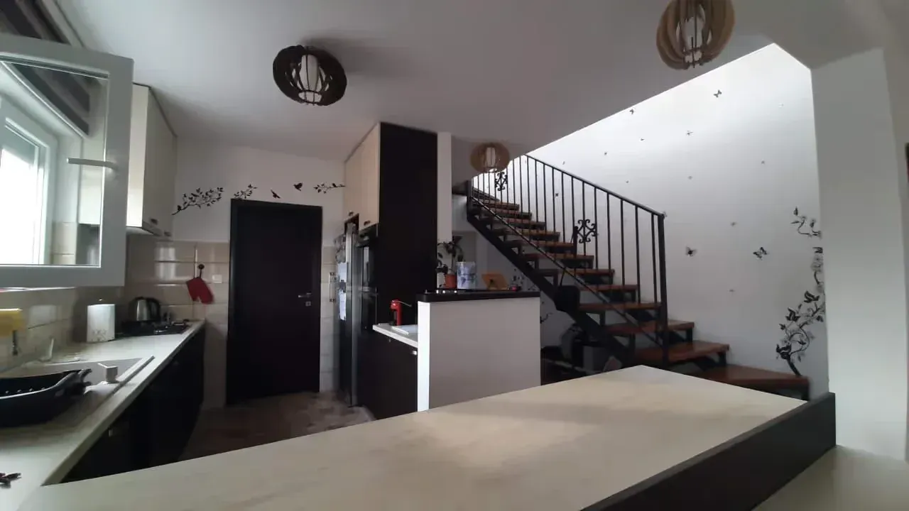 Kuhinja sa radnim dijelom i stepeništem u pozadini.