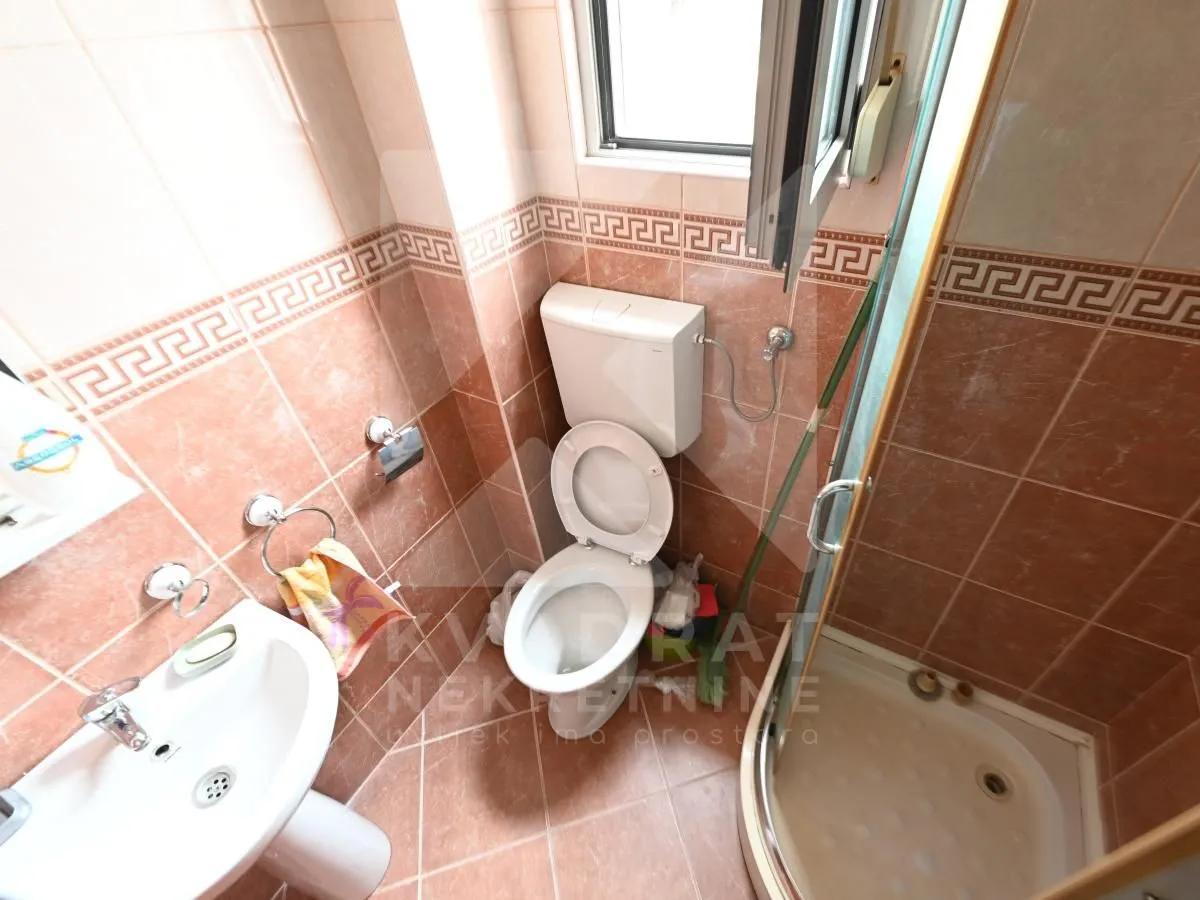 Small bathroom with a shower cabin and brown ceramic tiles.