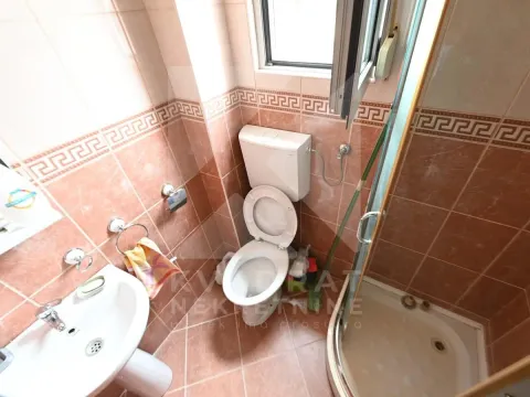 Small bathroom with a shower cabin and brown ceramic tiles. - image 4