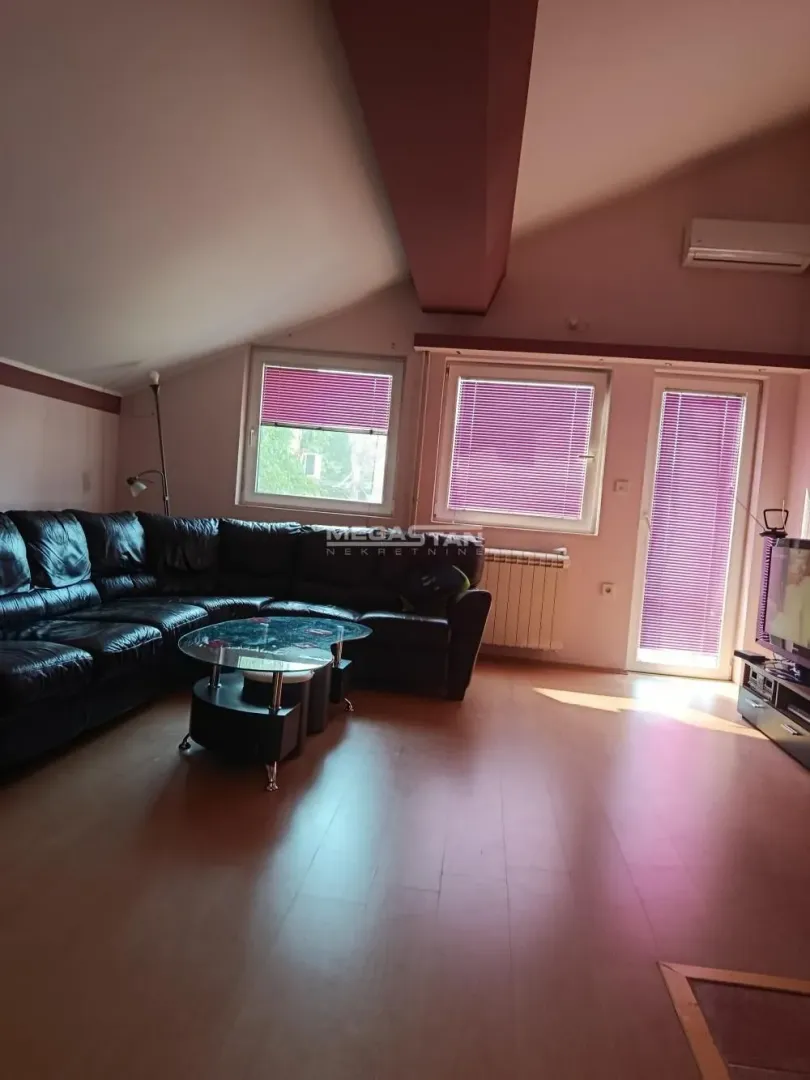 Living room with a corner sofa, coffee table, and sloping ceiling.
