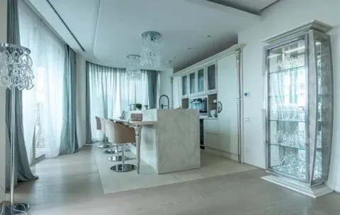 Modern kitchen with a bar counter and dining table in light tones. - image 10