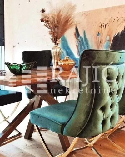 Dining area with a wooden table and green upholstered chairs.