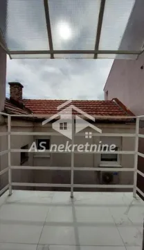 Natkriveni balkonski prostor sa belom ogradom i pogledom na krovove susednih zgrada. - image 15