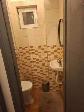 Small bathroom with tiles, washbasin, and toilet. - image 2
