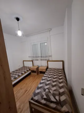 A simple bedroom featuring two single beds and nightstands. - image 5