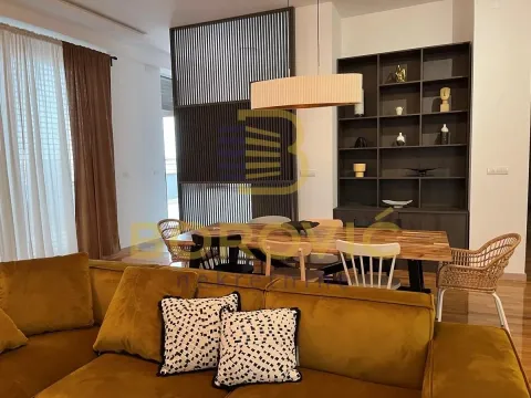 Living room with a sofa and a dining area in the background. - image 2