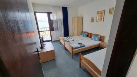 Spavaća soba sa tri kreveta, ormarom i izlazom na terasu sa pogledom na more. - image 11